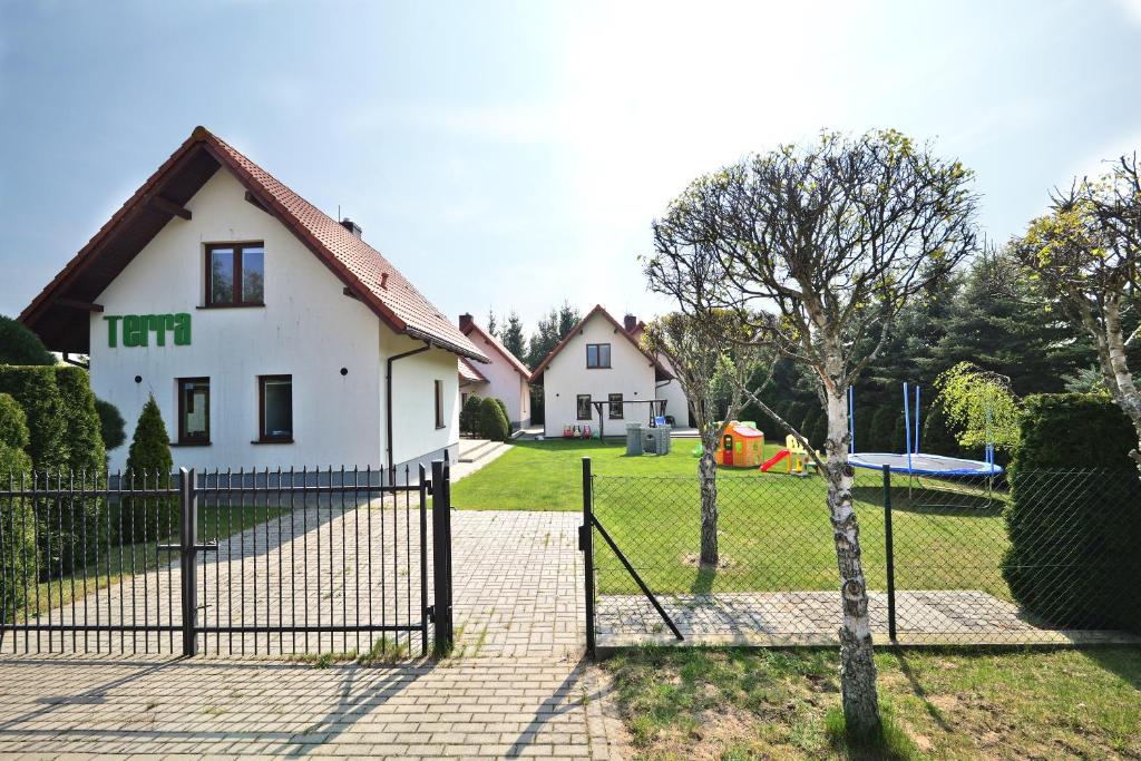 a fence in front of a house with a playground at Domki TERRA in Debina