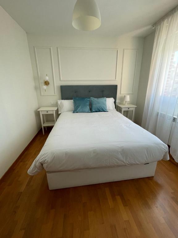 a bedroom with a large white bed with blue pillows at Apartamento Lardero Garnacha Rioja in Lardero