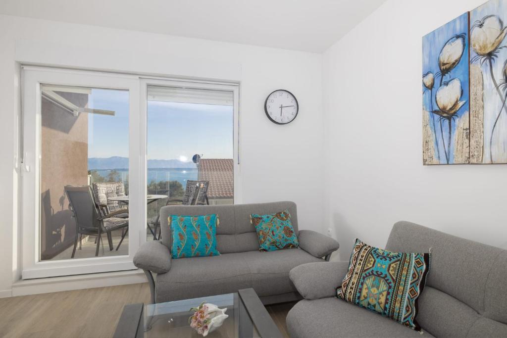 a living room with a couch and a clock on the wall at Apartman MORE Živogošće in Živogošće
