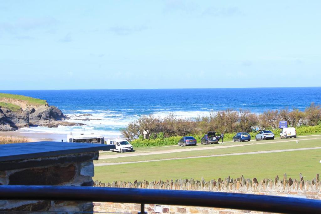 eine Gruppe von Autos, die auf einer Straße neben dem Meer geparkt sind in der Unterkunft BY THE BEACH, The Quies, Beach House in Saint Merryn