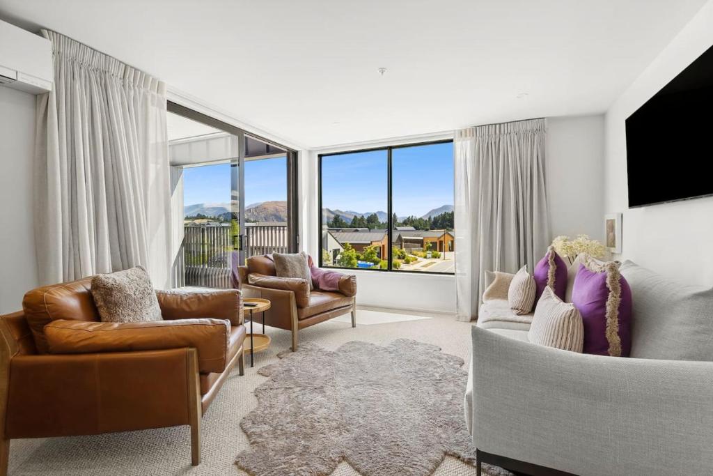 a living room with couches and chairs and a large window at Mountainview Escape | Stylish, BBQ, and Parking in Wanaka