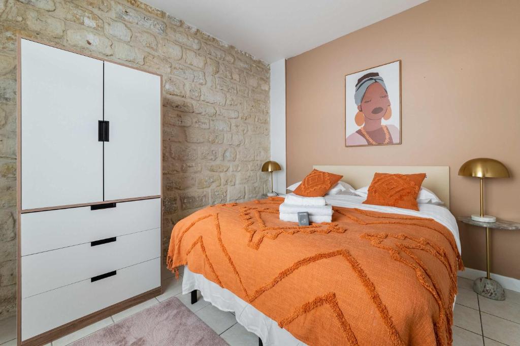 Cette chambre comprend un lit avec des draps orange et une commode. dans l'établissement Appartement familial proche des commerces - 8P - FLAT-GUEST, à Paris
