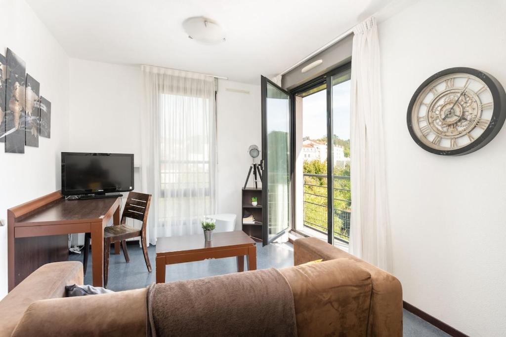 - un salon avec un canapé, un bureau et un réveil dans l'établissement le Valmy avec balcon, à Lyon