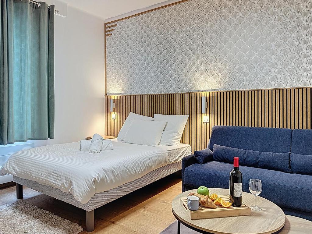 une chambre avec un lit et un canapé bleu dans l'établissement Le Nid - Paris - Le Blanc Mesnil, au Blanc-Mesnil