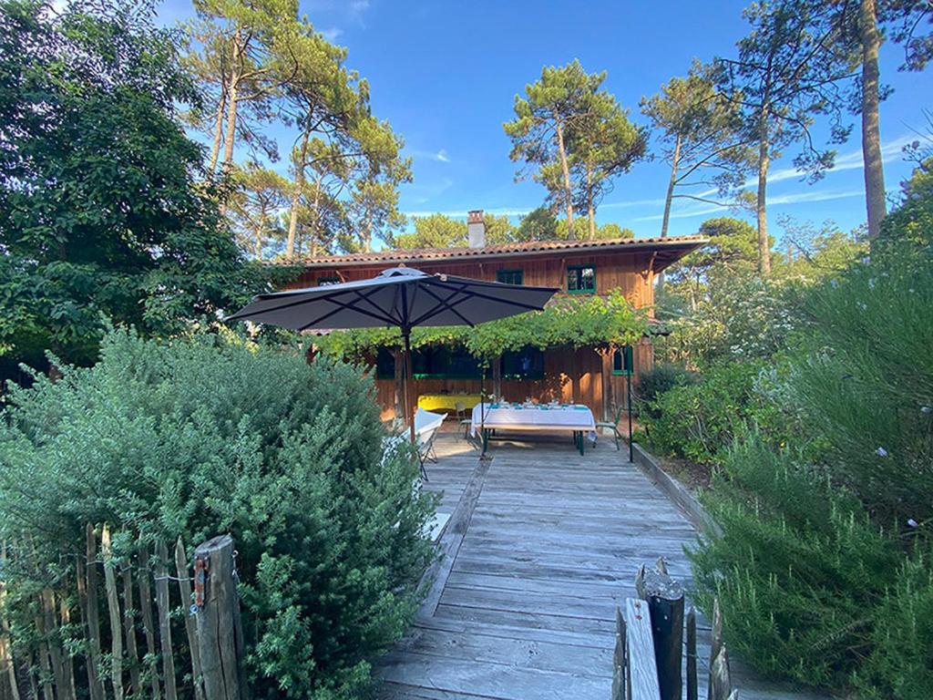 une terrasse avec un parasol en face d'une maison dans l'établissement Villa MÉJEANNE, à Lège-Cap-Ferret