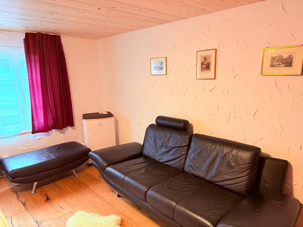a living room with a leather couch and a window at Vintage Apartment By Apartments Capricorn in Gsteigwiler