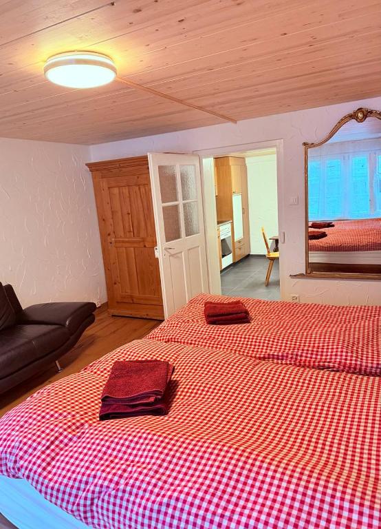a bedroom with a large bed with a red checkered blanket at Vintage Apartment By Apartments Capricorn in Gsteigwiler