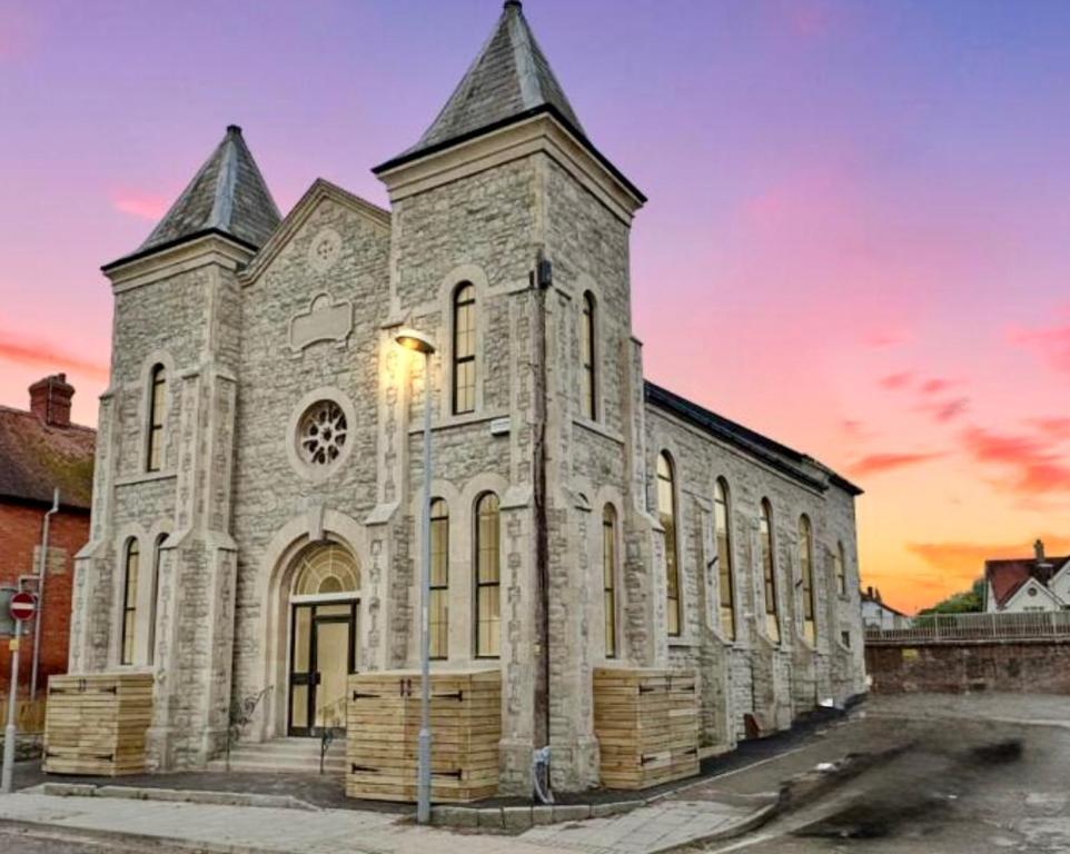 an old stone church with a sunset in the background at Hurley - A Converted Church Luxe Apartment in Gillingham