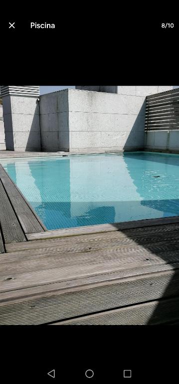 Una gran piscina azul con terraza de madera. en Estudio con piscina comunitaria, en Vigo