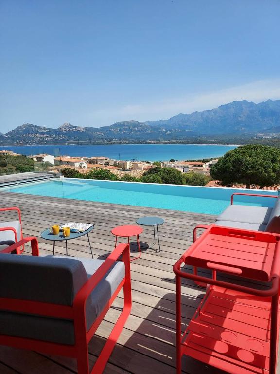 une terrasse avec des chaises et des tables ainsi qu'une piscine dans l'établissement Villa avec vue panoramique sur la baie, à Calvi