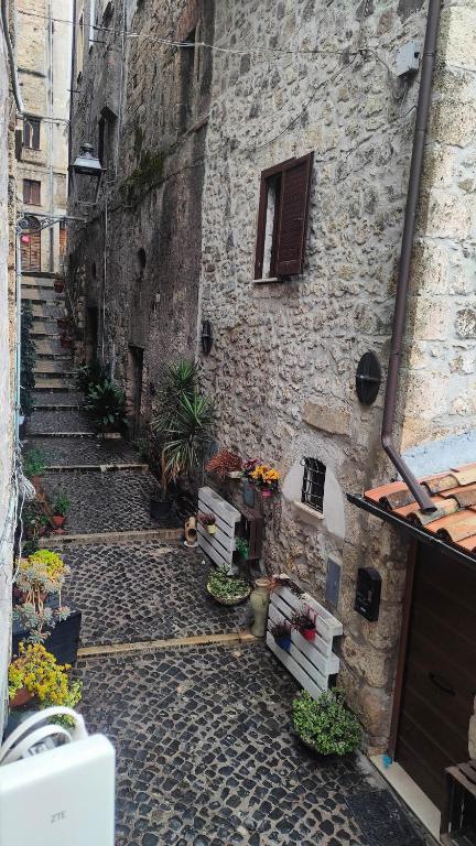 un vicolo con un edificio in pietra con scale e fiori di Secret Room Anagni ad Anagni