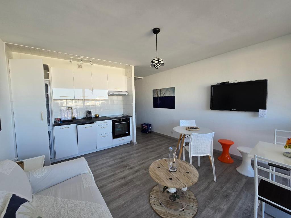 un salon avec un canapé et une table et une cuisine dans l'établissement Appartement rénové proche port et plages, à Saint Cyprien Plage
