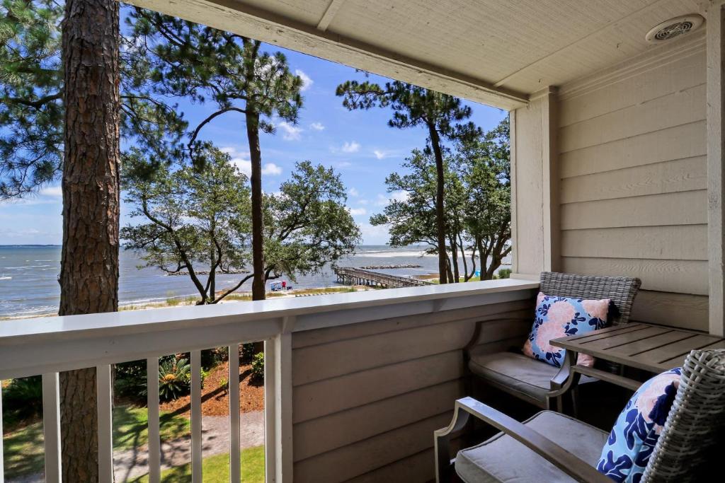 a screened in porch with a table and chairs and the ocean at Oceanfront Sunrises on Mitchelville Beach in Hilton Head Island