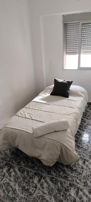 a bed in a white room with a pillow on it at Calle platano37 in Valencia