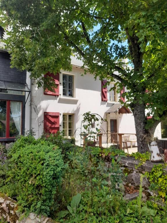 une maison blanche avec une porte rouge et des arbres dans l'établissement Gîte avec restaurant privatisé, à Biollet
