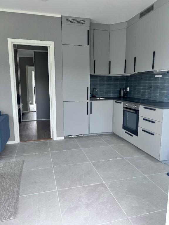 a kitchen with white cabinets and a tile floor at Newly built, bright apartment in Skien