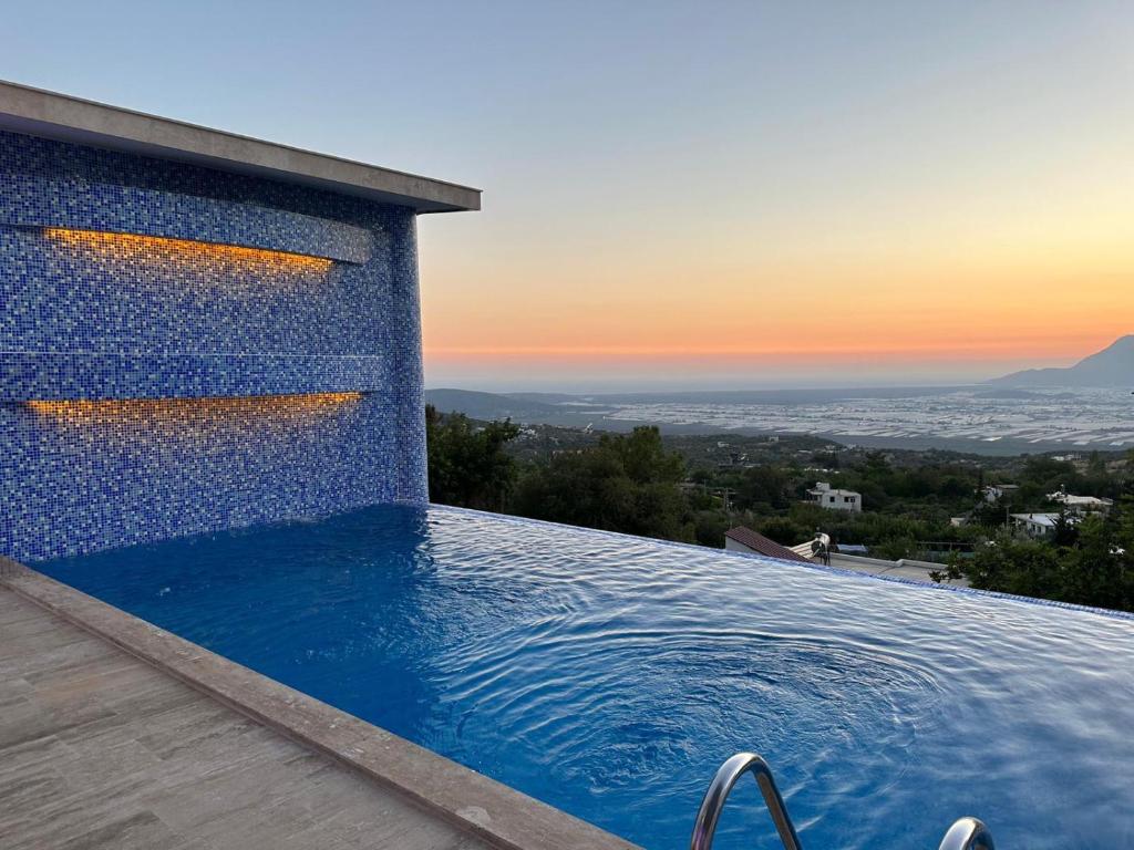 a swimming pool on the side of a house with a sunset at Kalkan da Vaıllant Villa in Kaş