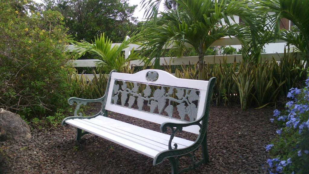 a white bench in a garden with plants at L'escapade in Sainte-Anne