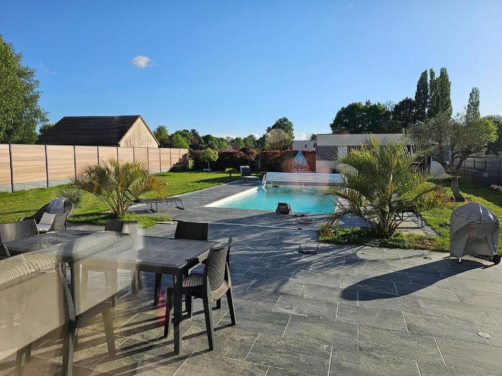 un patio avec une table et des chaises à côté d'une piscine dans l'établissement Le Mans spécial 24h, à Changé