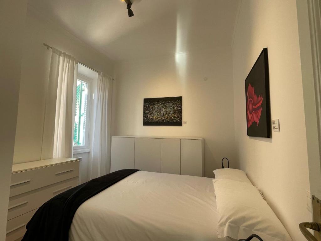 a white bedroom with a bed and a window at Docking House in Lido di Ostia