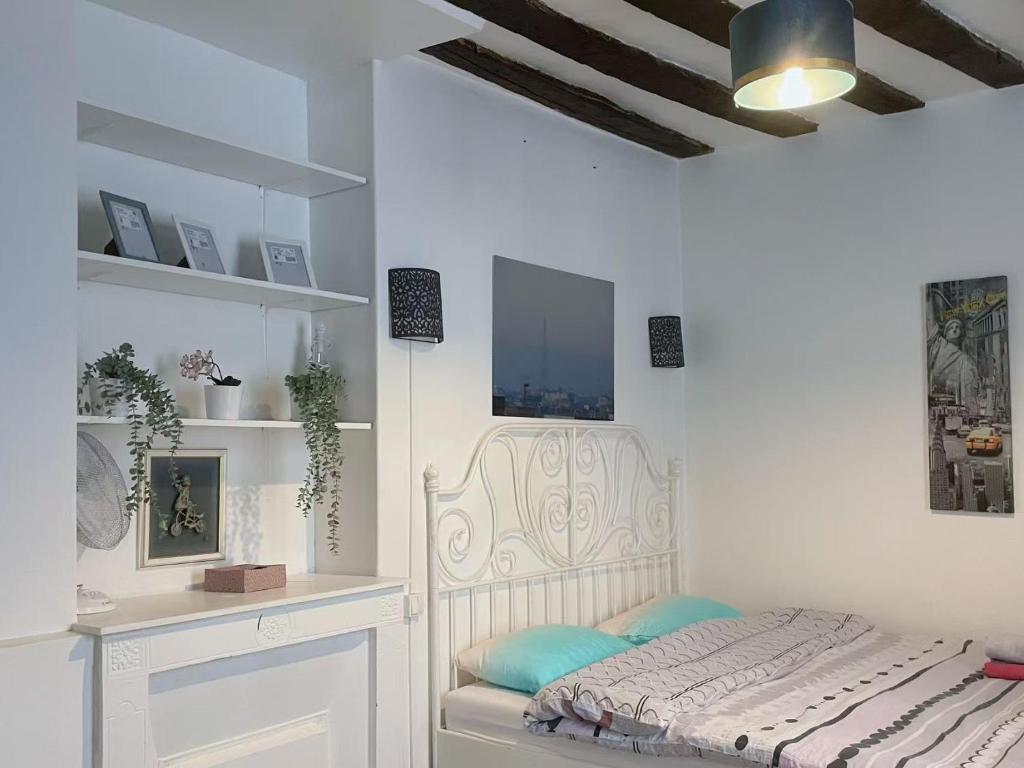 une chambre avec un lit dans une pièce blanche dans l'établissement Studio in central Paris, à Paris