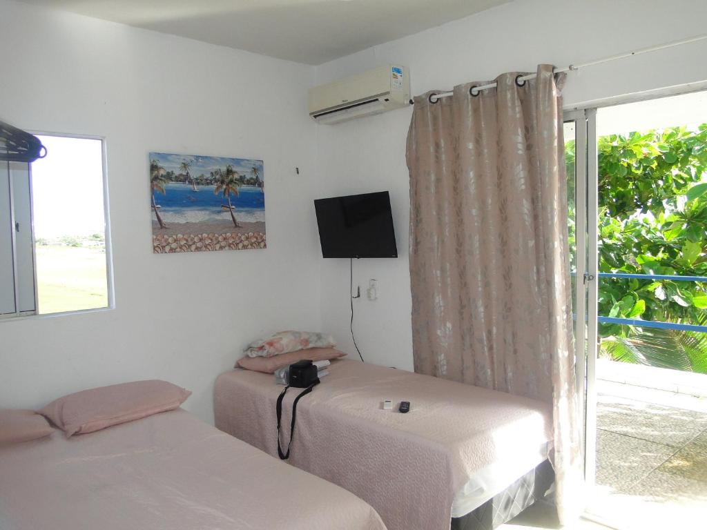 a room with two beds and a tv and a window at MaréVila Taíba - Casa de Praia com Wi-fi e Vista para o mar in Taíba