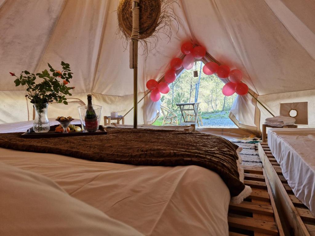 a bed in a tent with a table with red balloons at Glamping Montanejos in Montanejos