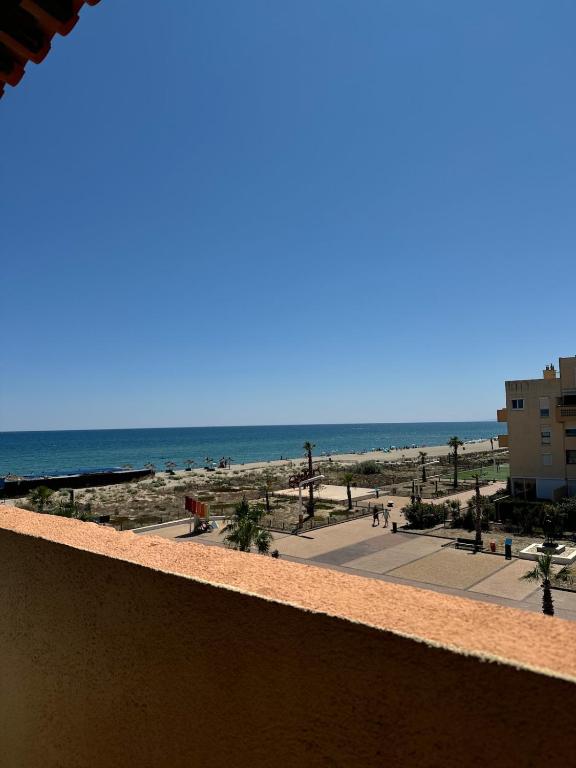 ein Blick auf den Strand vom Balkon eines Resorts in der Unterkunft Charmant appartement vue mer in Le Barcarès