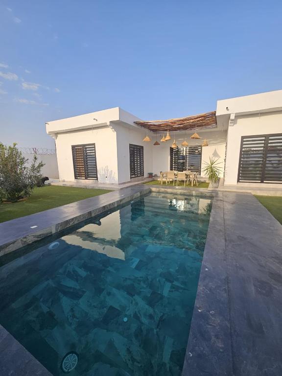 a swimming pool in front of a house at Villa Nossa in Keur Goonde