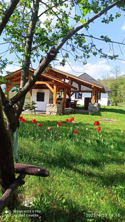 a house with a bench in a field of flowers at Casa Livada Bunicii in Târgu Ocna