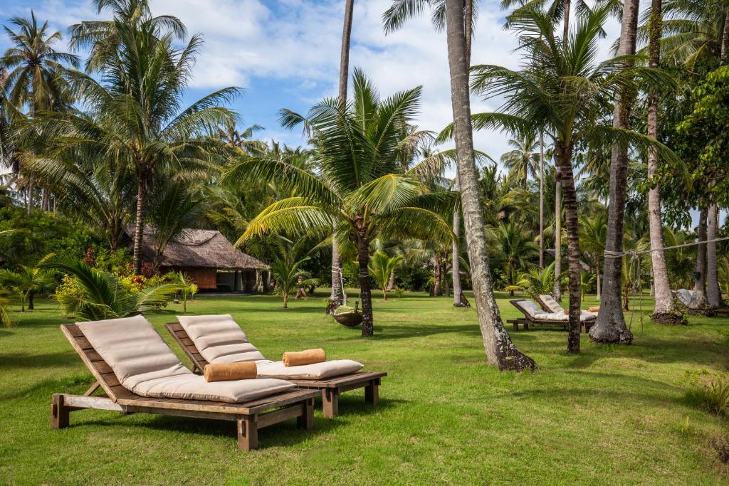 a group of lounge chairs in a yard with palm trees at Koyao Island Resort in Ko Yao Noi