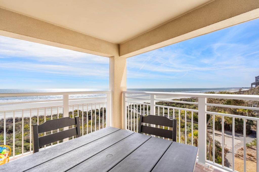 Un gran balcón con una mesa de madera y dos sillas. en 5120 Windswept Villa by Akers Ellis Rentals, en Kiawah Island