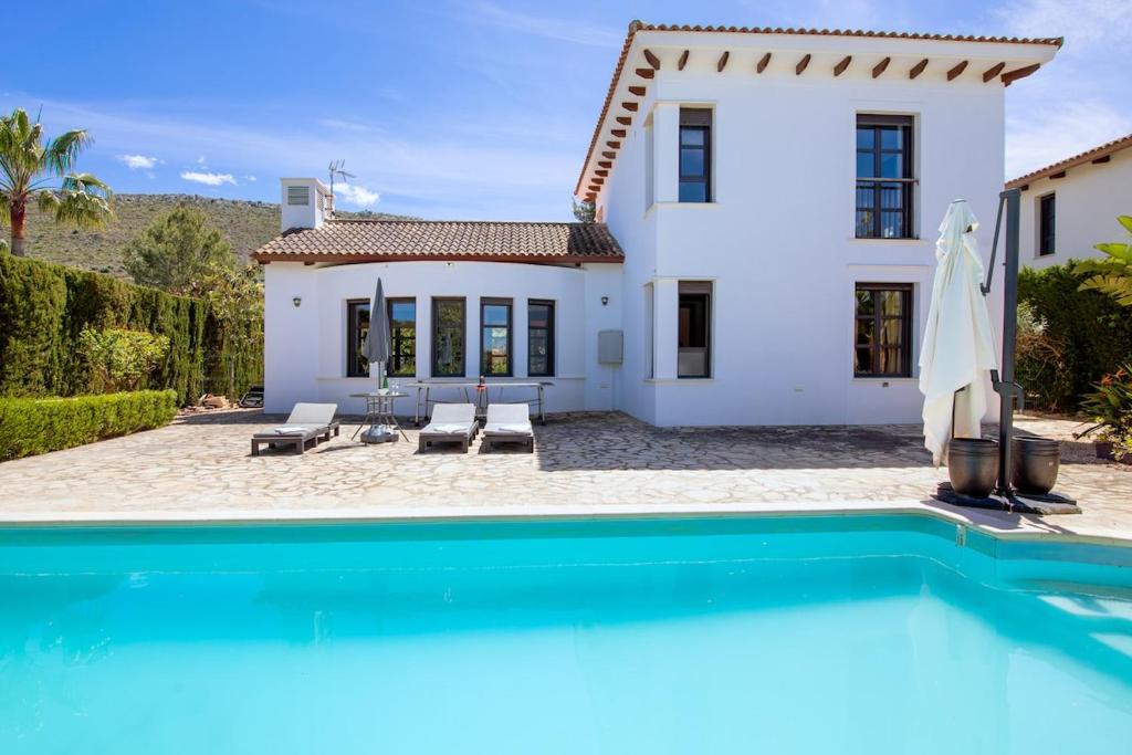 a villa with a swimming pool in front of a house at Villa Siegfried JÁVEA in Benitachell