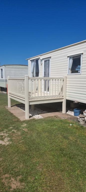 a white rv with a porch and a house at Peaces caravan 8 berth on coral beach in Ingoldmells