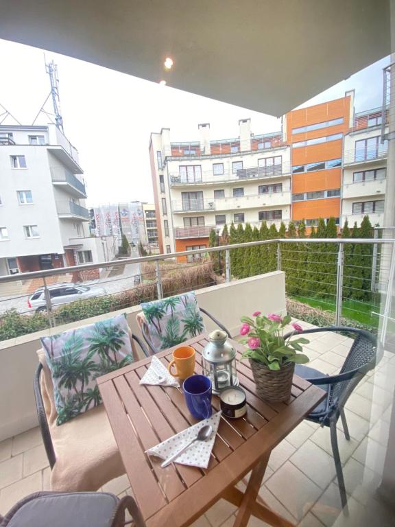 a wooden table on a balcony with a view of a building at Wave and Sun Apartment in Hel