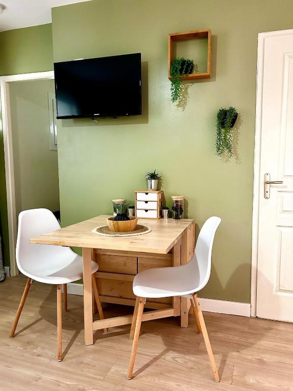 une table de salle à manger avec deux chaises et une télévision au mur dans l'établissement Studio cosy proche hyper centre et gare, à Banyuls-sur-Mer