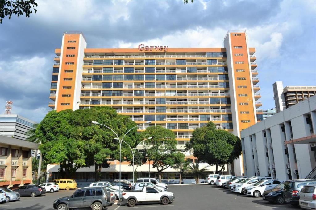 a large building with cars parked in a parking lot at Happy Hotel Garvey Park in Brasília