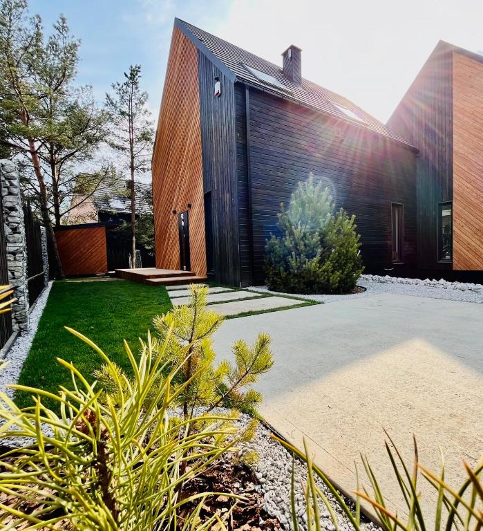 a house with a wooden facade with a yard at Willa Horyzont Borsk in Borsk