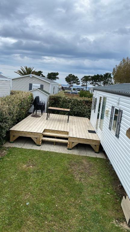 un banc assis sur une terrasse en bois à côté d'une maison dans l'établissement Mobil-Home le 70 du White Port, à Dinard