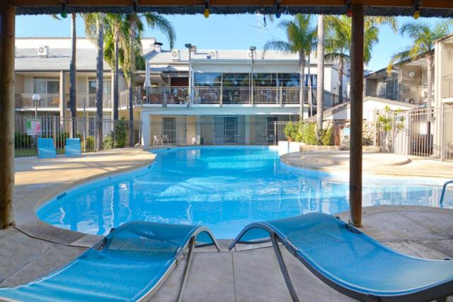 a large blue swimming pool with a slide in front of a building at Mandurah Motel and Apartments in Mandurah