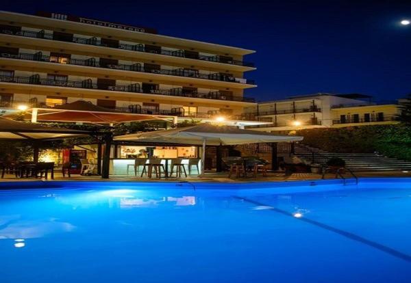 a large swimming pool in front of a building at night at Merope Hotel in Karlovasi
