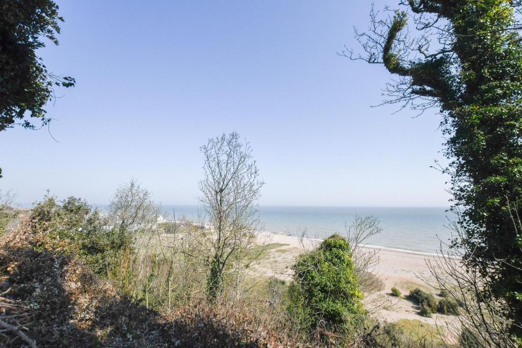 een uitzicht op het strand door de bomen bij Chalet Eighteen in Deal