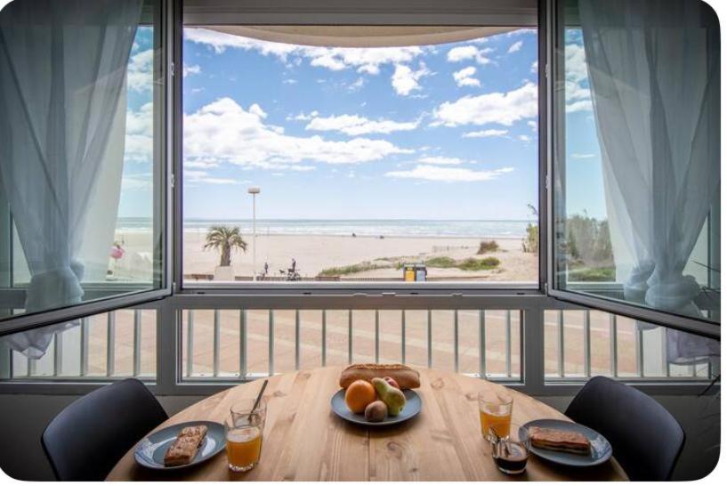 - une table avec une assiette de fruits et une vue sur la plage dans l'établissement La Rose des Sables, à La Grande Motte