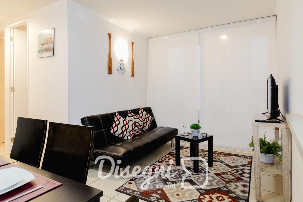 ein Wohnzimmer mit einer schwarzen Ledercouch und einem Tisch in der Unterkunft Disegni 02 - Departamento Av del Mar La Serena Sector Casino Enjoy in Coquimbo