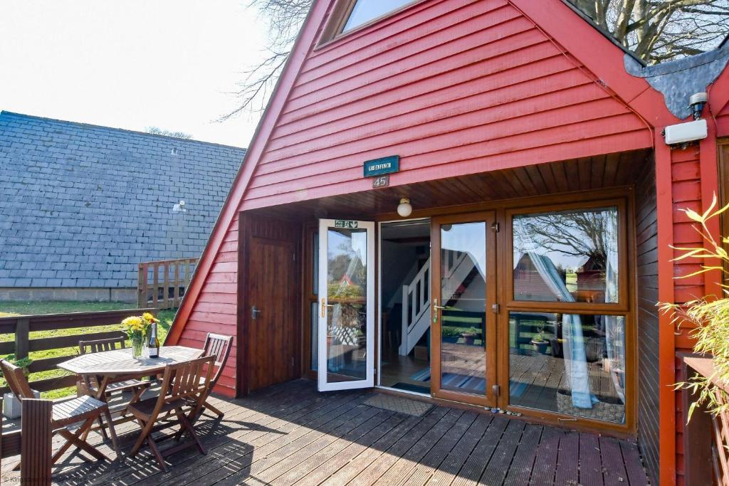 een rood huis met een tafel en stoelen op een terras bij Chalet Fortyfive in Deal