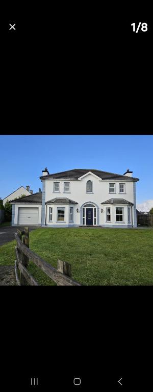 a large white house on a grassy field at Dungloe House in Dungloe