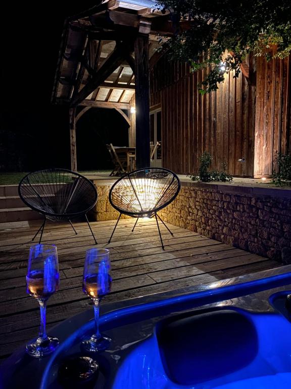 two chairs and two wine glasses on a deck at night at Gîte avec spa in Saint-Avit-Sénieur