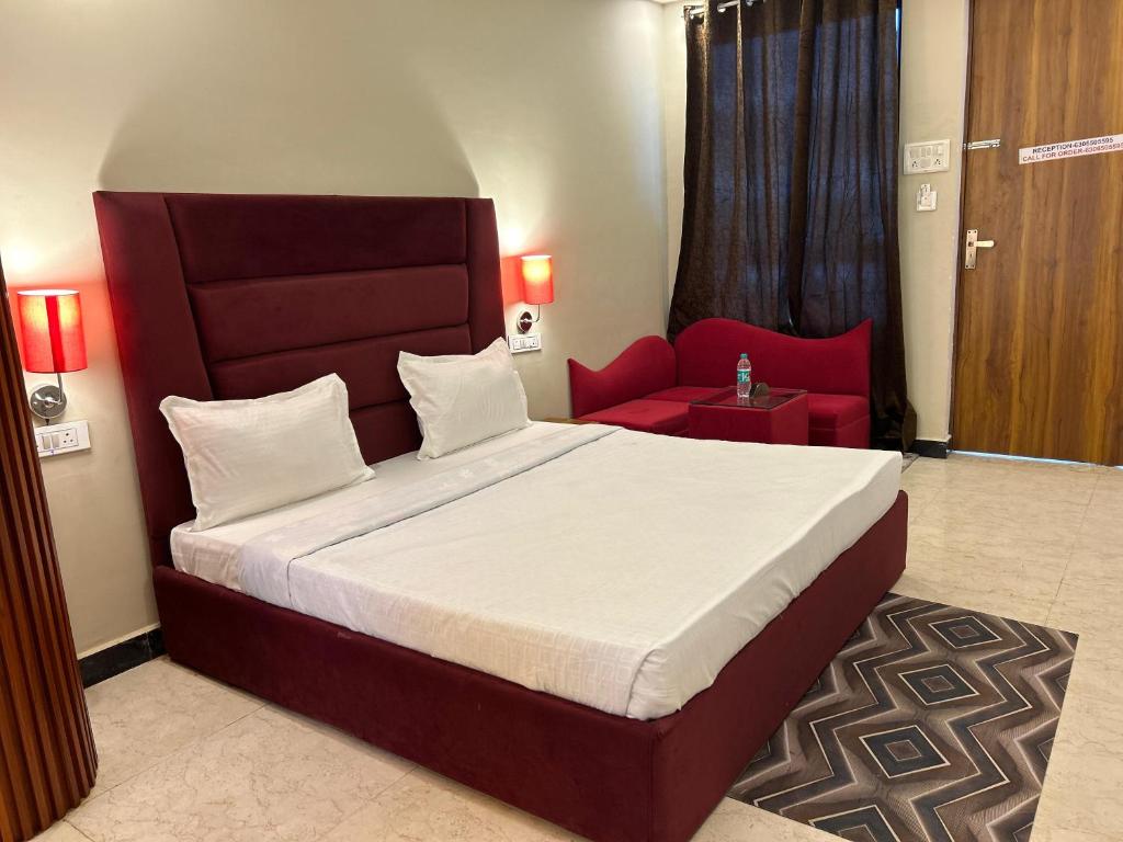 a bedroom with a large bed and a red chair at Hotels7Apple in Mahoba