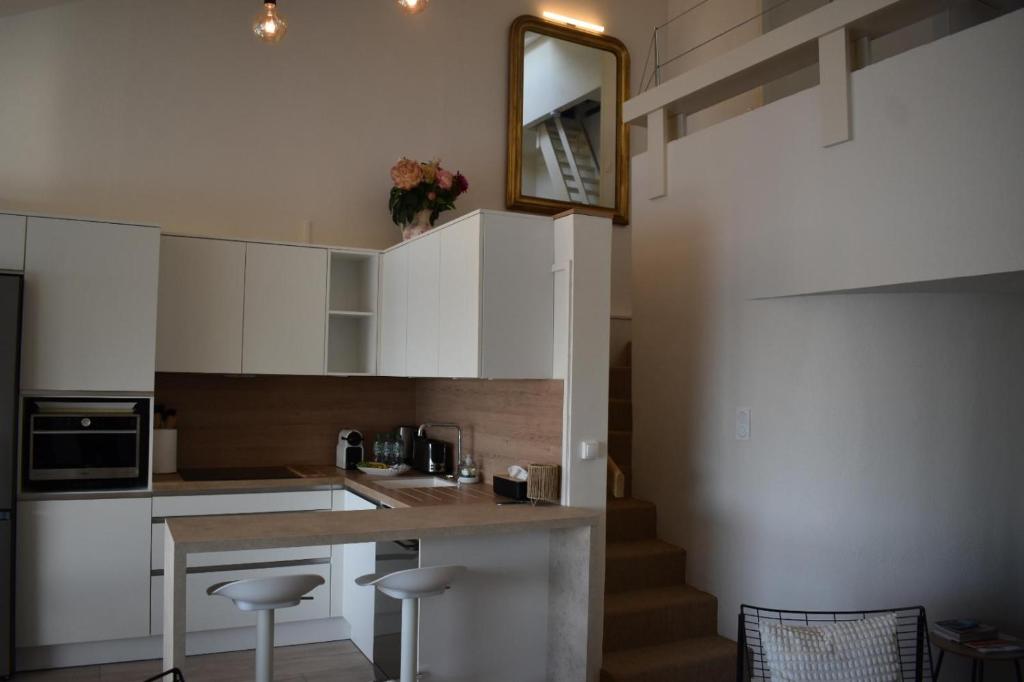 a kitchen with white cabinets and a table with stools at Bel appartement à Deauville - vue mer et port in Deauville