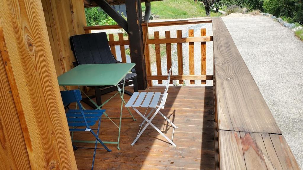 une table et deux chaises sur une terrasse en bois dans l'établissement Maison confortable avec balcon et coin terrasse, à Allemont